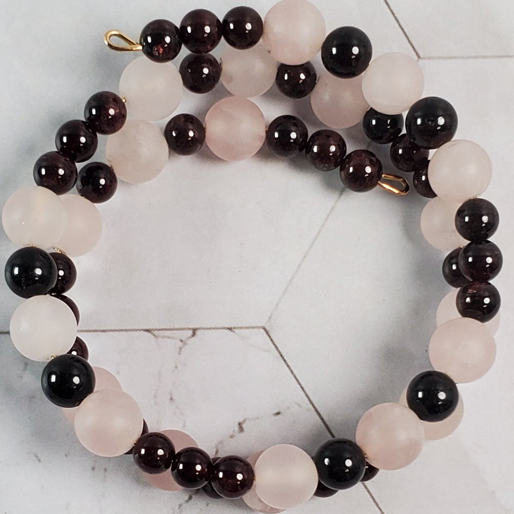 Bracelet with deep red and pink beads on a marble tile