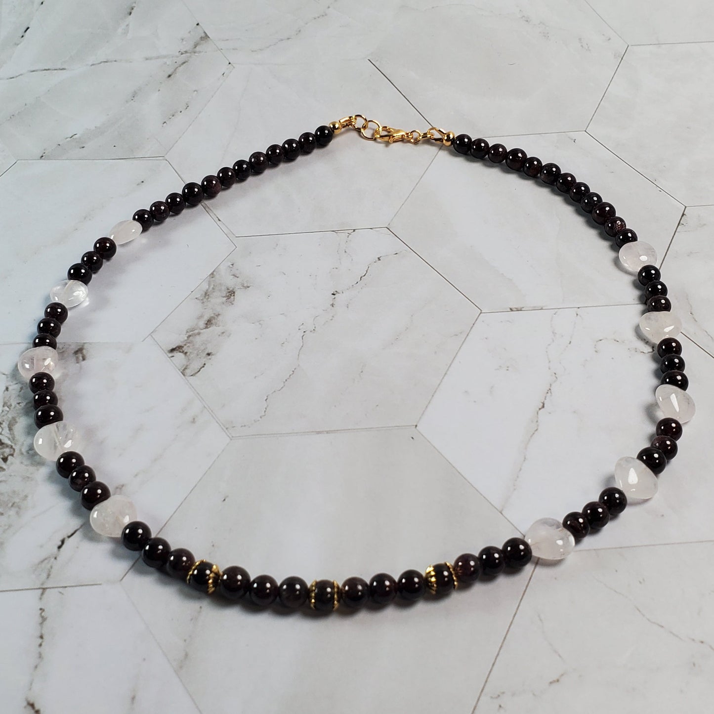 Necklace with dark red and pink beads on a marble surface