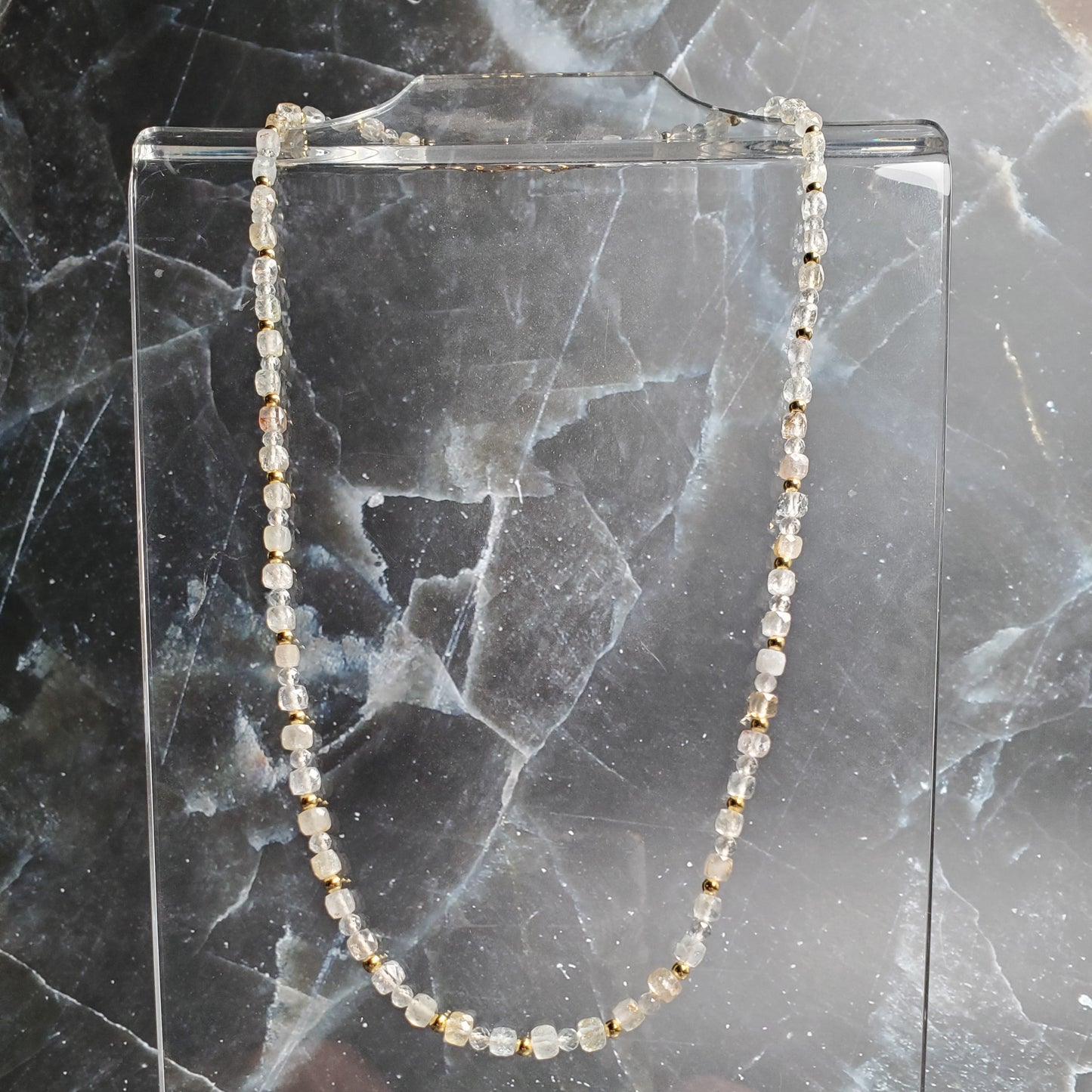 Gold beaded necklace on a marble surface