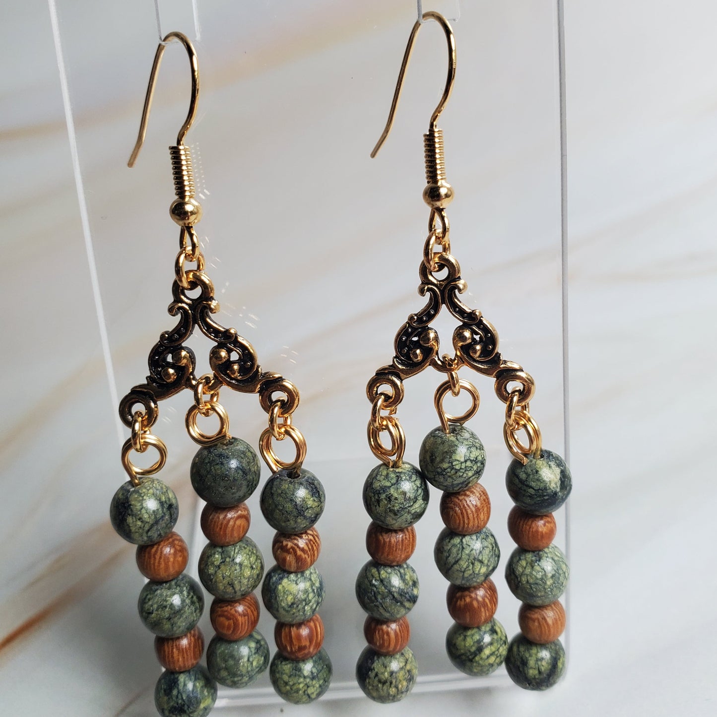 Beaded earrings on a clear stand against a light background