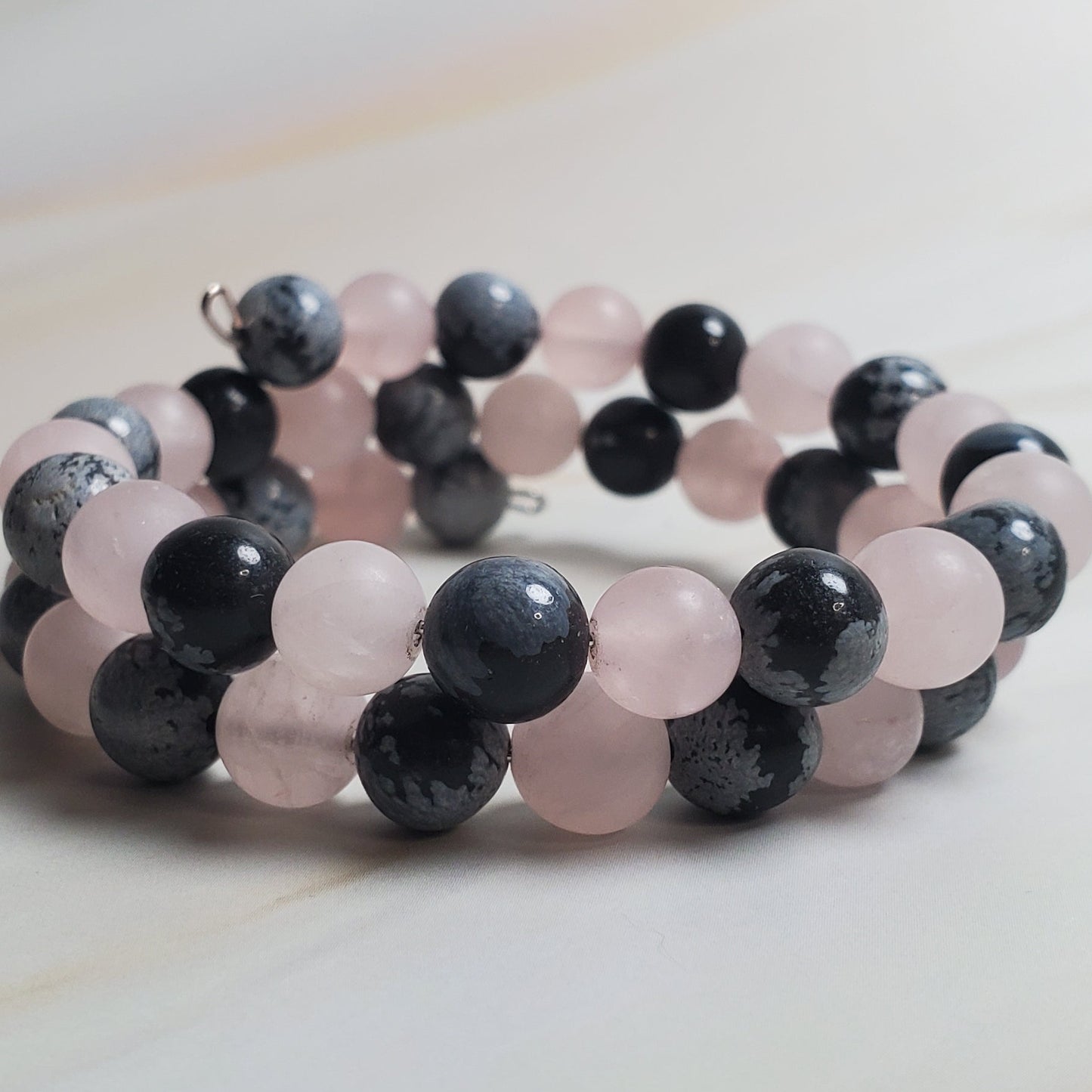 Beaded bracelet with pink and black beads on a light wooden surface