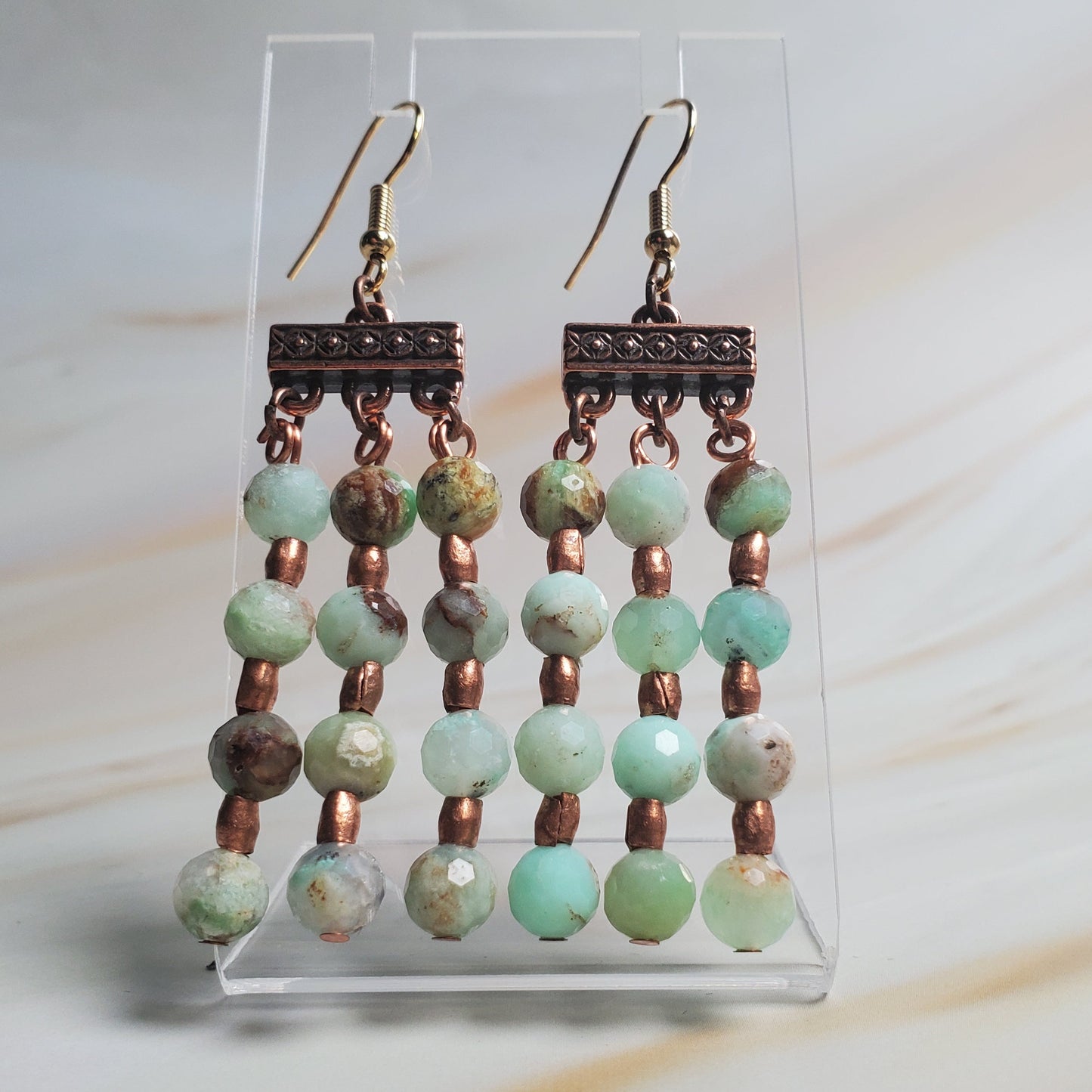 Pair of beaded earrings on a clear stand with a light background