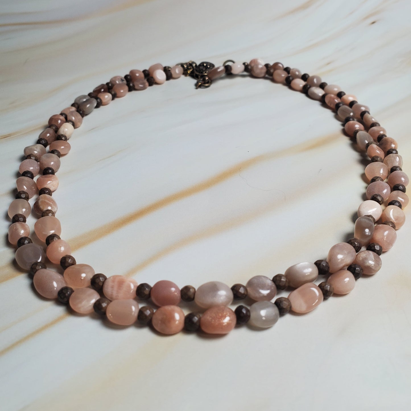Necklace with pink and brown beads on a marble surface