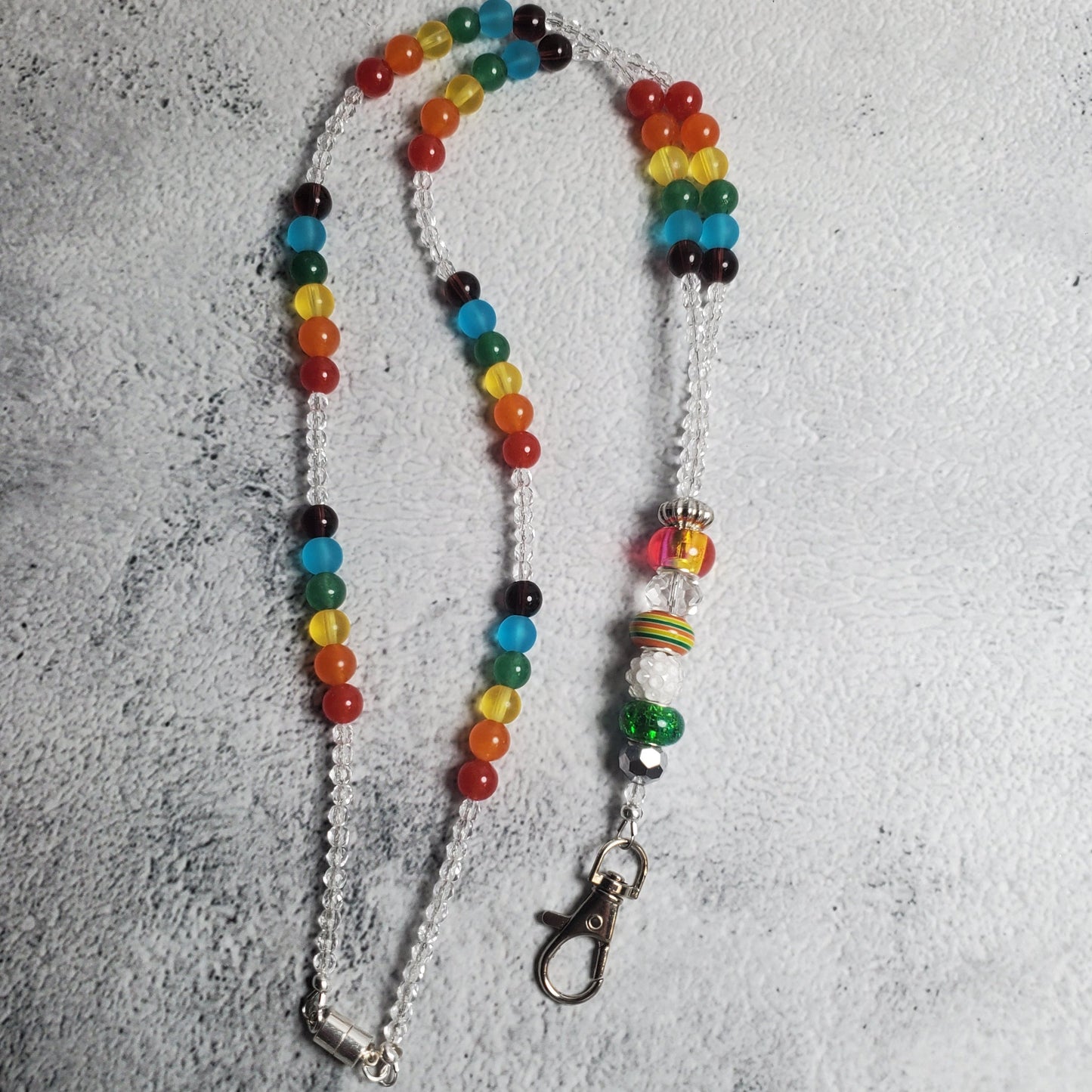Vibrant rainbow lanyard with colorful glass beads and decorative charm beads, featuring a secure lobster claw clasp and magnetic closure for keys and badges.
