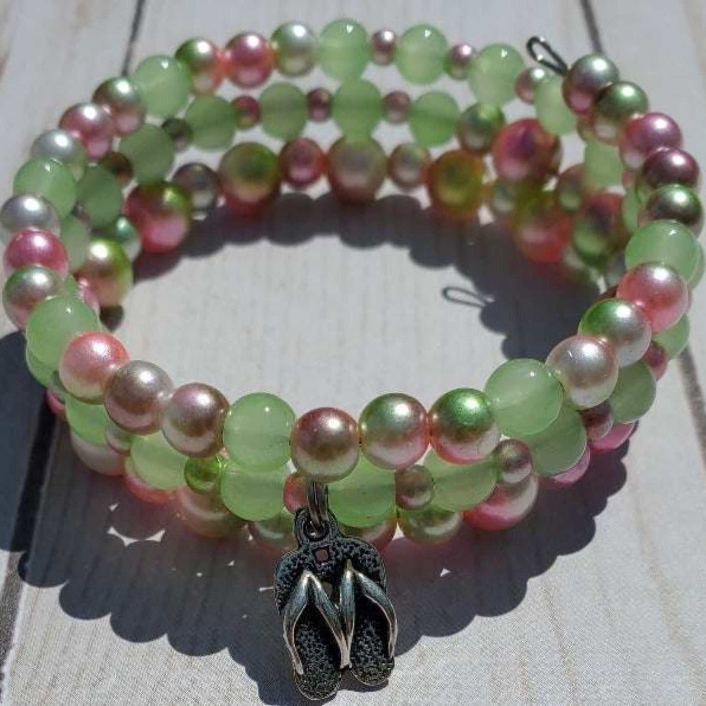 Colorful charm bracelet with green, pink, and pearl beads featuring a pewter flip flop charm on memory wire for summer style.