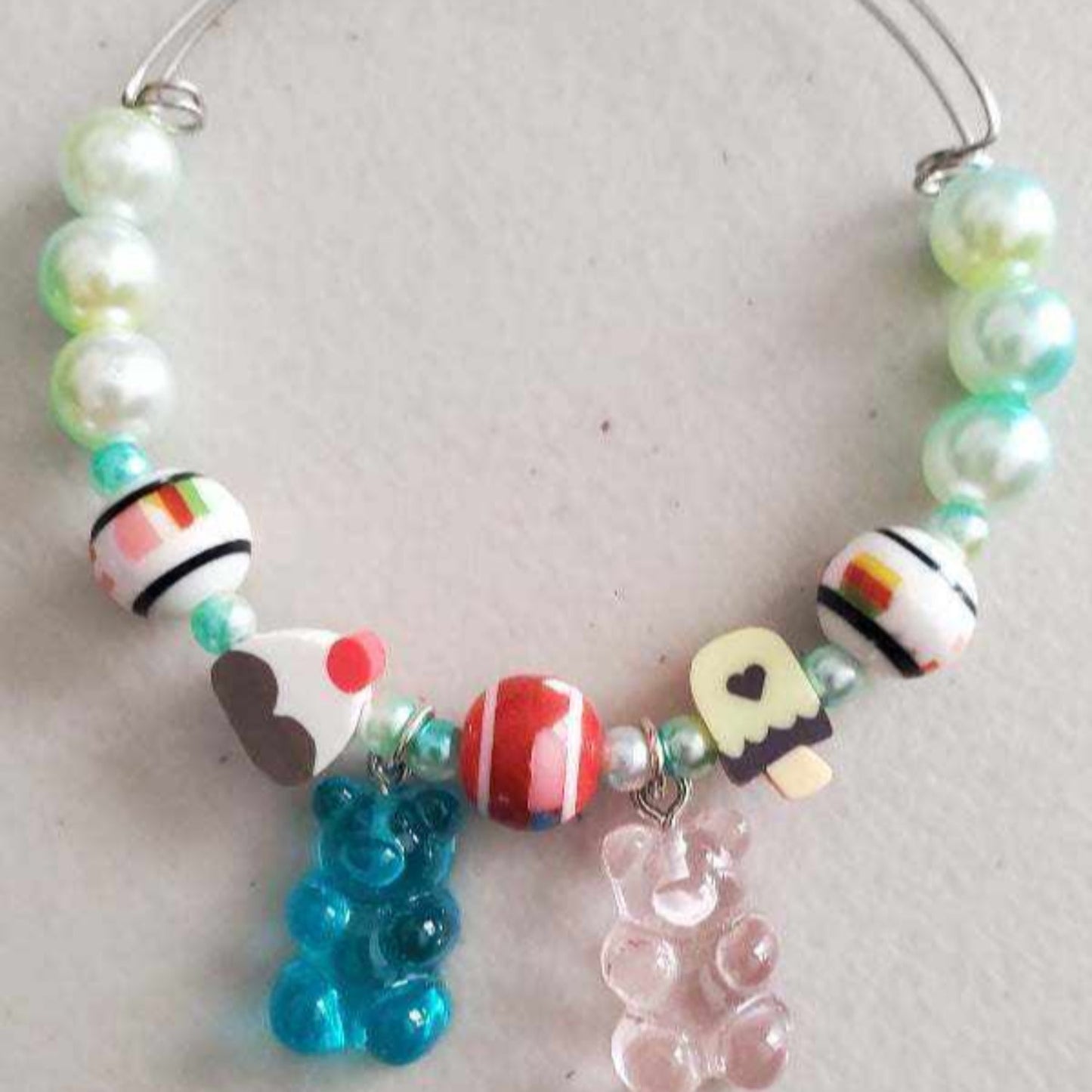 Colorful charm bracelet with gummy bear and candy-shaped beads on adjustable wire bangle