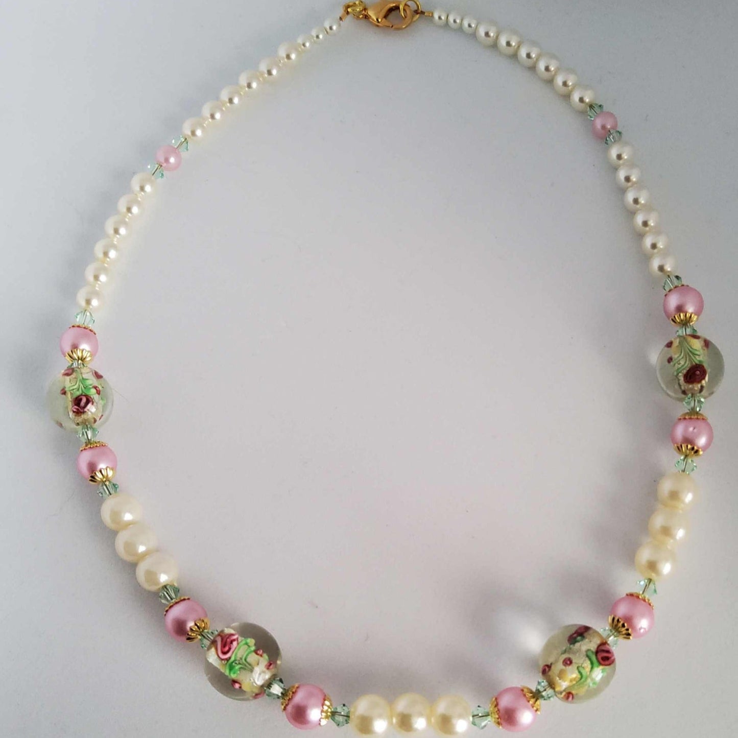 Classic pearl necklace with ivory pearls, glass lampwork rose beads, peridot-green crystals, and brass clasp