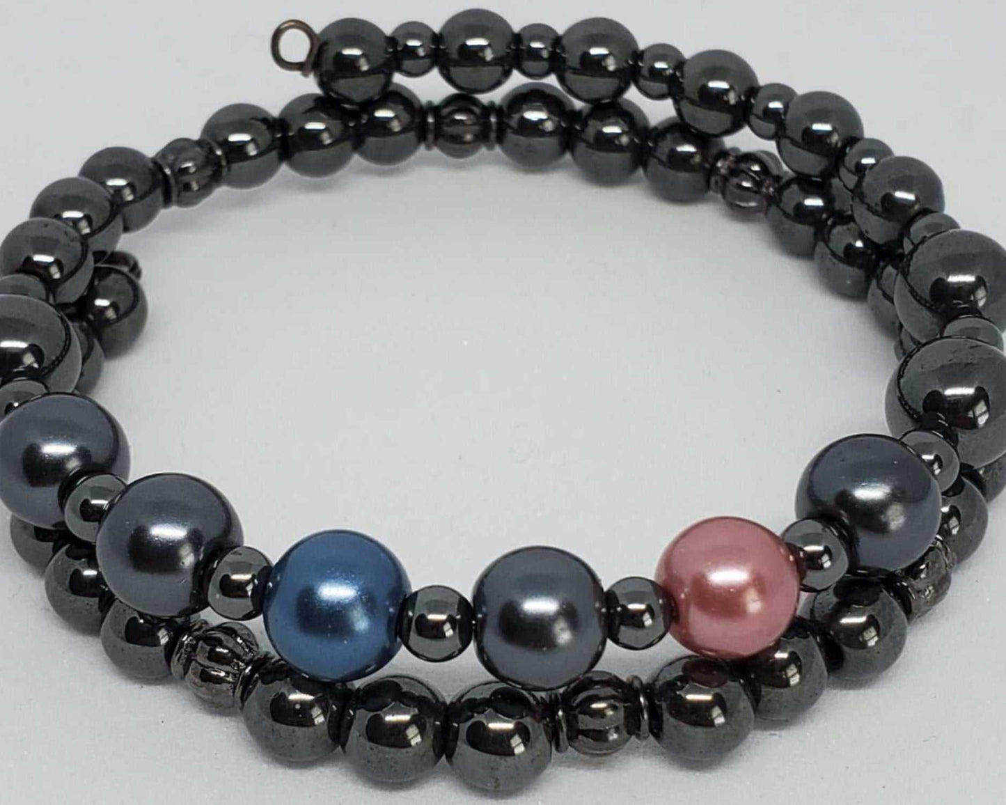 Adjustable gemstone bracelet with metallic hematite beads and colorful pearl accents in blue and pink.