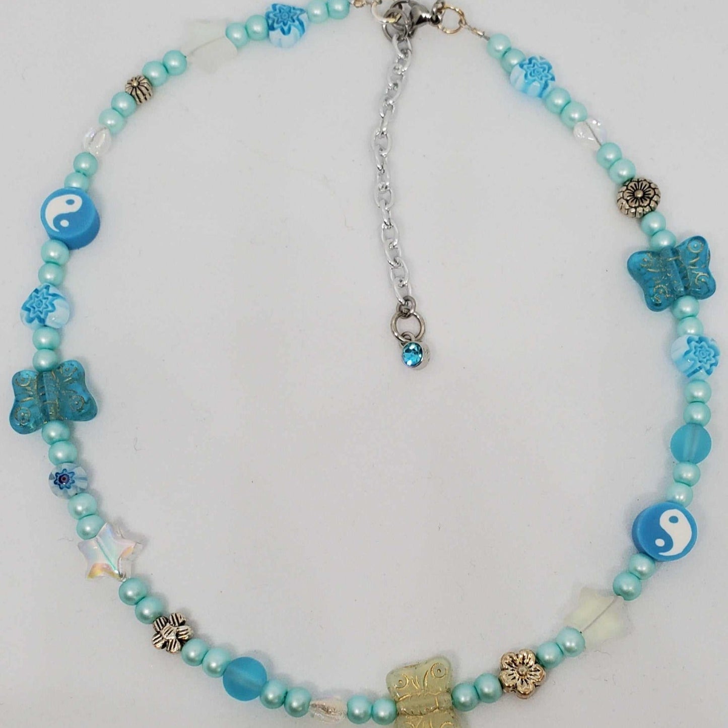 Blue and turquoise floral necklace with beads, butterflies, and yin-yang charms
