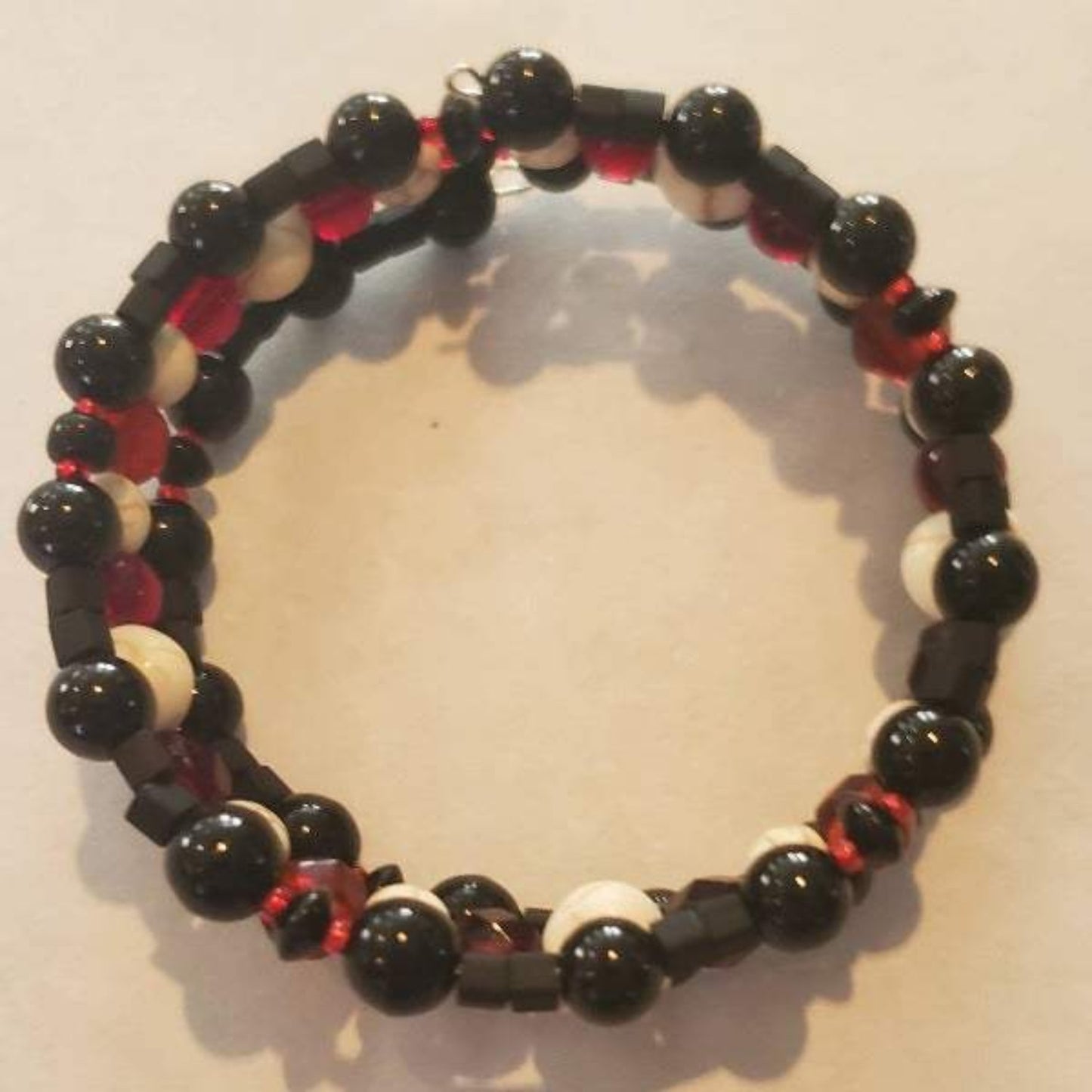 White Howlite skull bracelet with black and red beads on adjustable memory wire cuff, gothic Halloween style accessory
