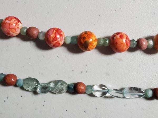 Close-up of aquamarine and orange multi-strand gemstone bracelet with natural wood and acrylic beads