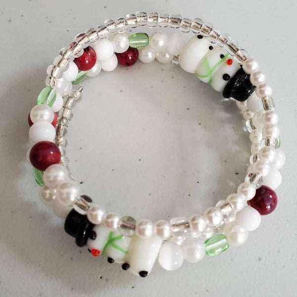 Holiday bracelet with snowman beads, green crystals, red and white beads, and acrylic pearls on adjustable memory wire.