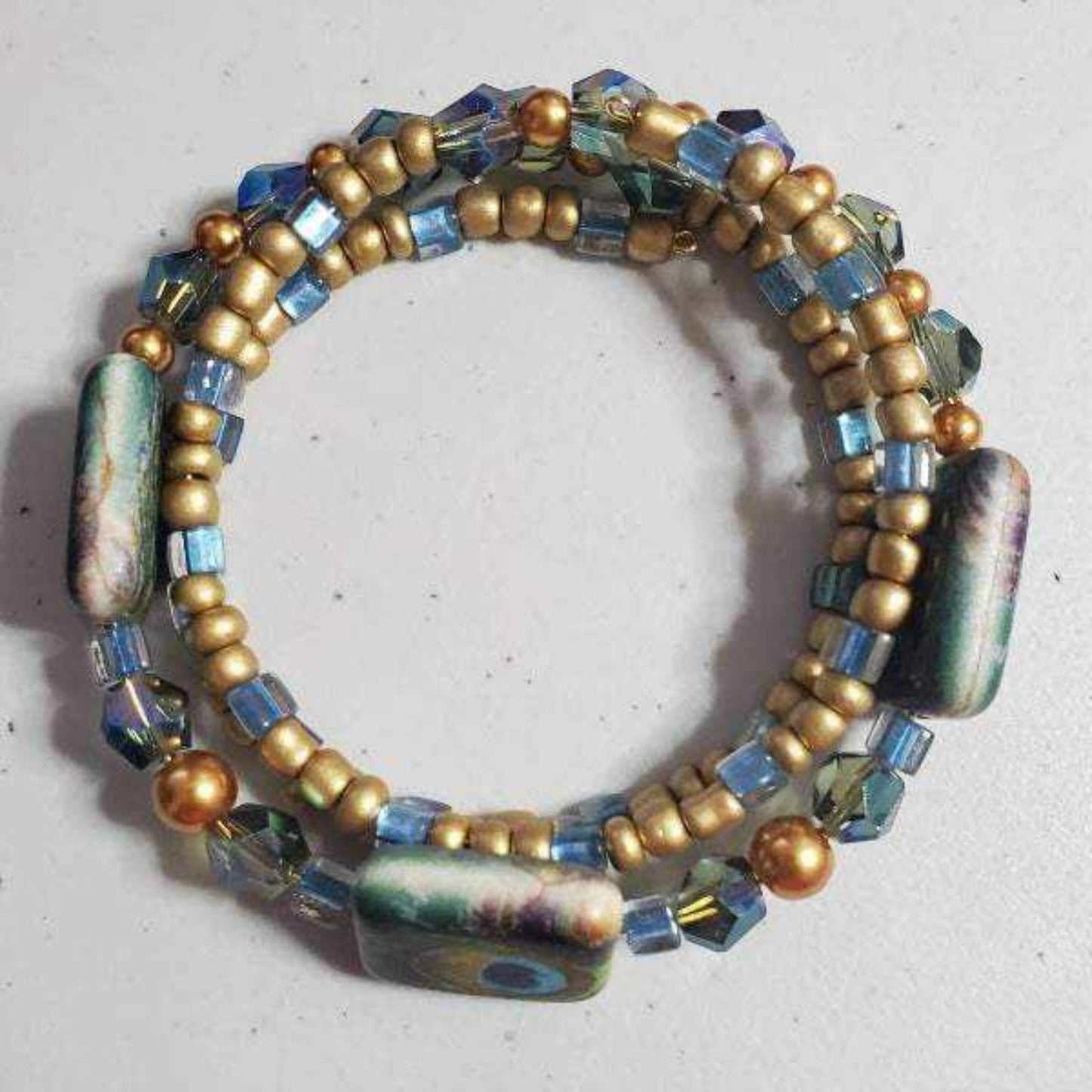 Vintage fashion peacock-inspired memory wire cuff bracelet with glass, crystal, acrylic, and resin beads in blue and gold tones
