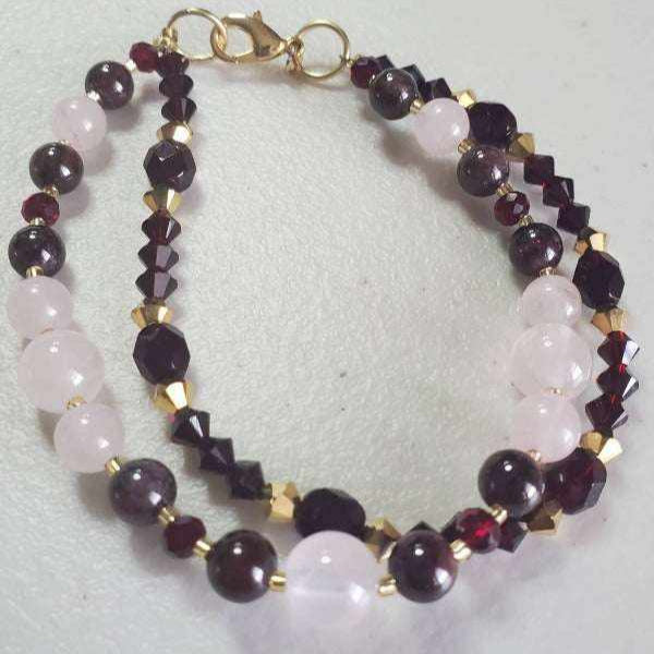 Double-strand gemstone bracelet featuring garnet, rose quartz, and gold Swarovski crystals with a lobster clasp