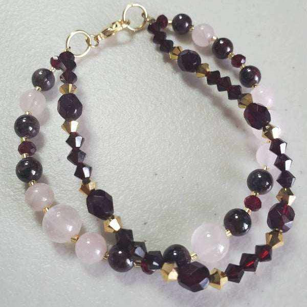 Double-strand gemstone bracelet with garnet, rose quartz, and gold Swarovski crystals, featuring a lobster claw clasp.