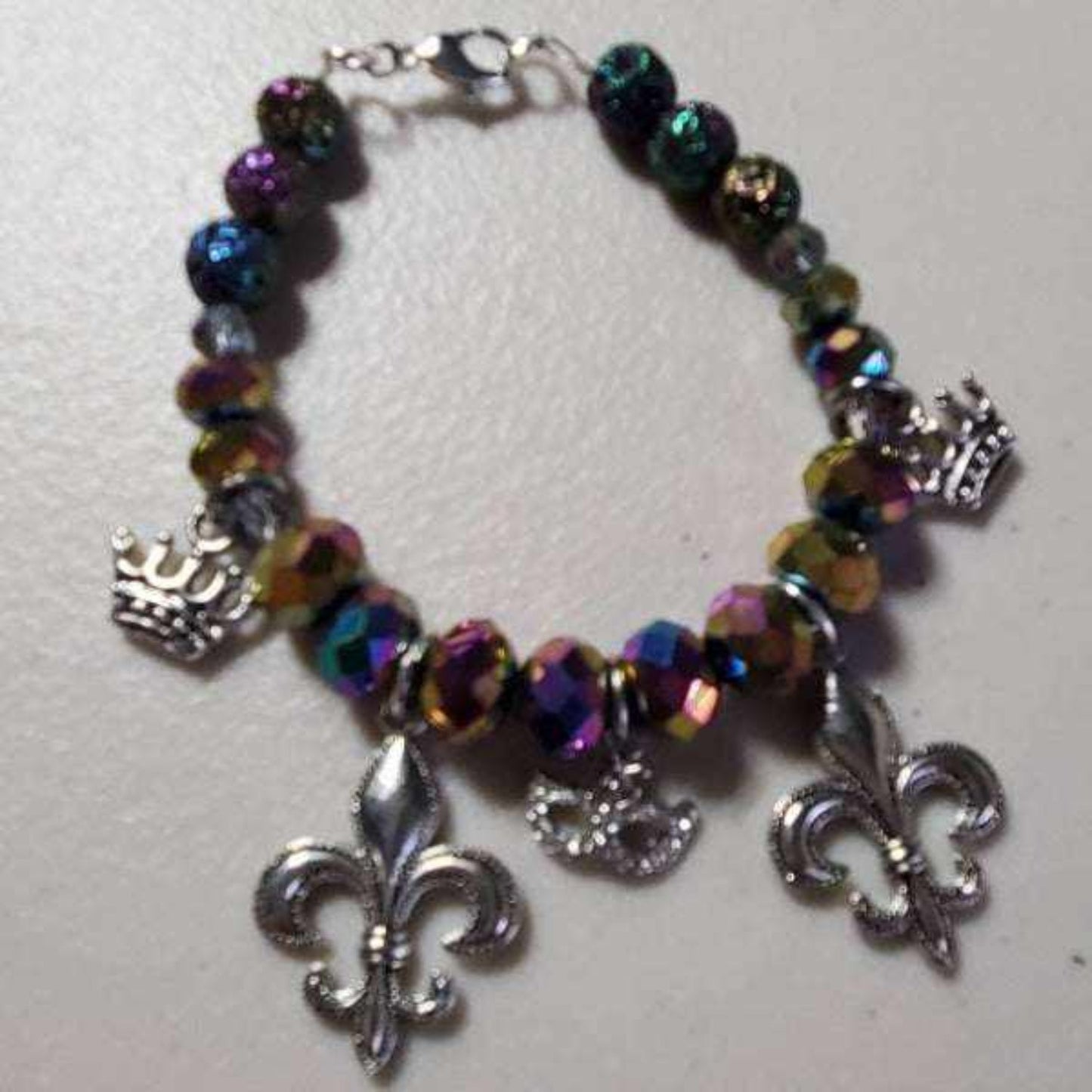 Silver tone Mardi Gras charm bracelet with colorful faceted beads and festive charms including fleur-de-lis, crown, and masquerade mask