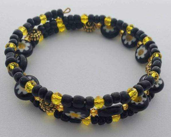 Black and white daisy floral bracelet with yellow crystal accents and adjustable memory wire cuff design