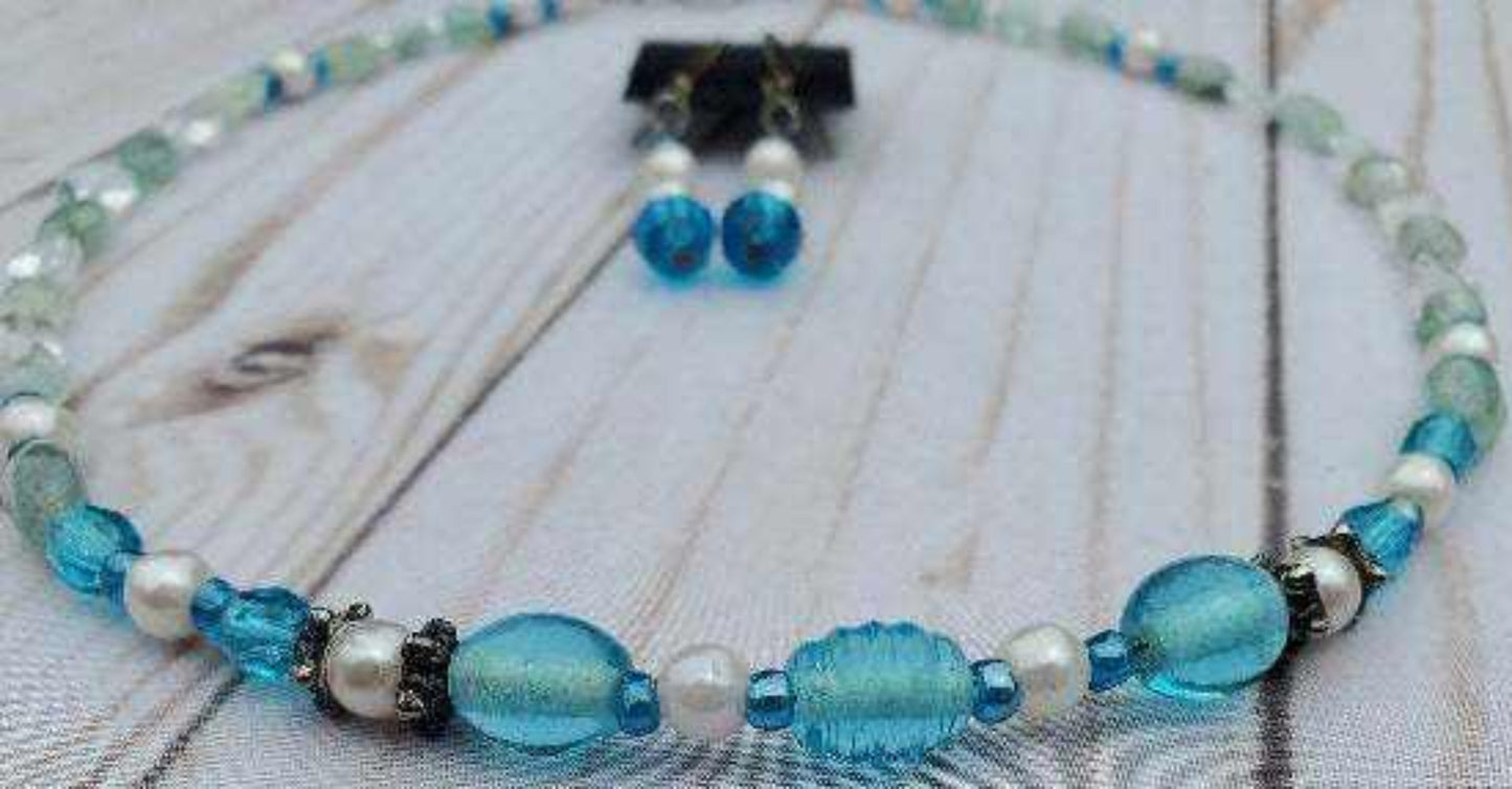 Aquamarine and pearl necklace and earring set with sterling silver accents on a wooden background