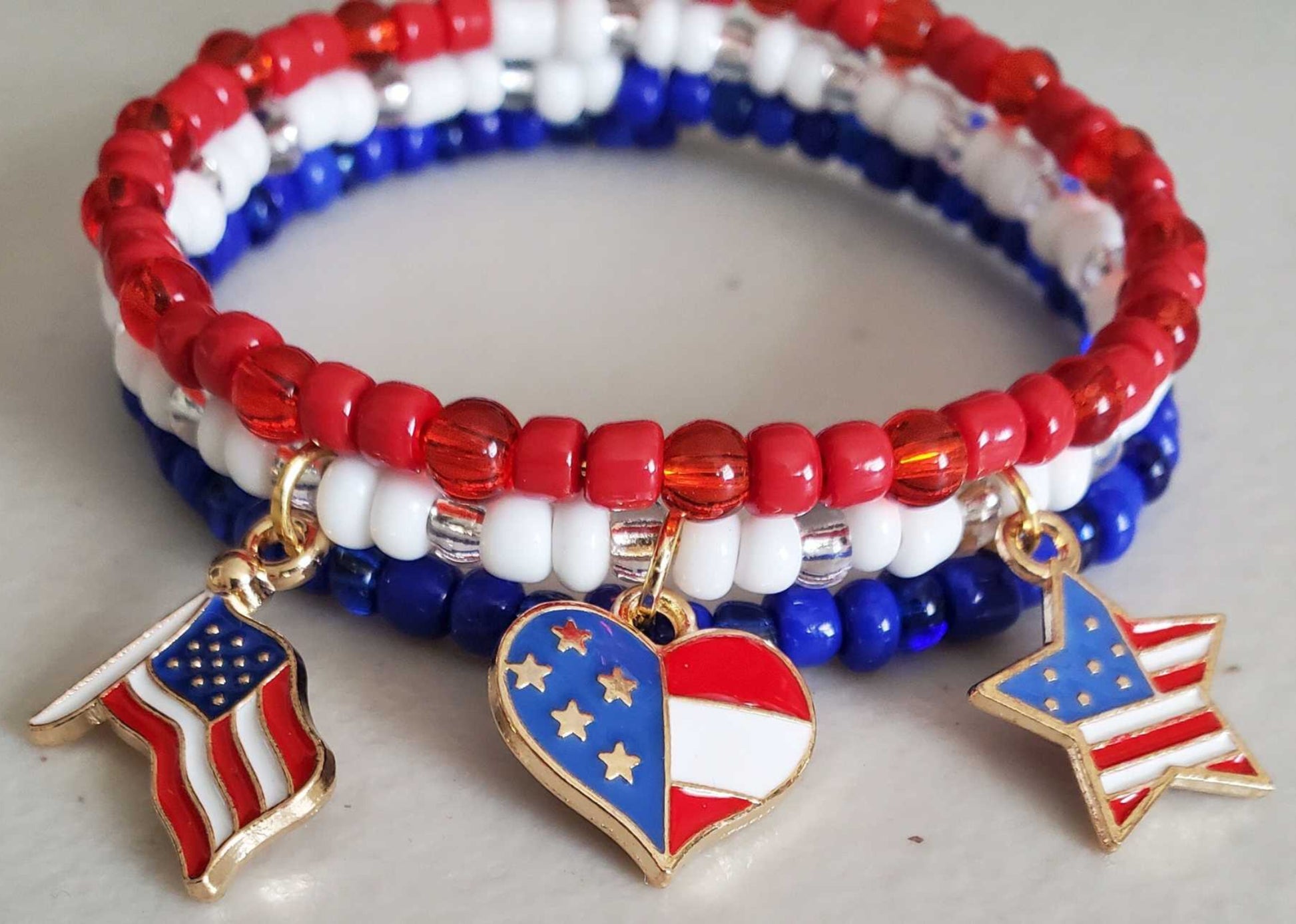 Red, white, and blue charm bracelet with Czech glass beads and brass charms shaped like flags, hearts, and stars.
