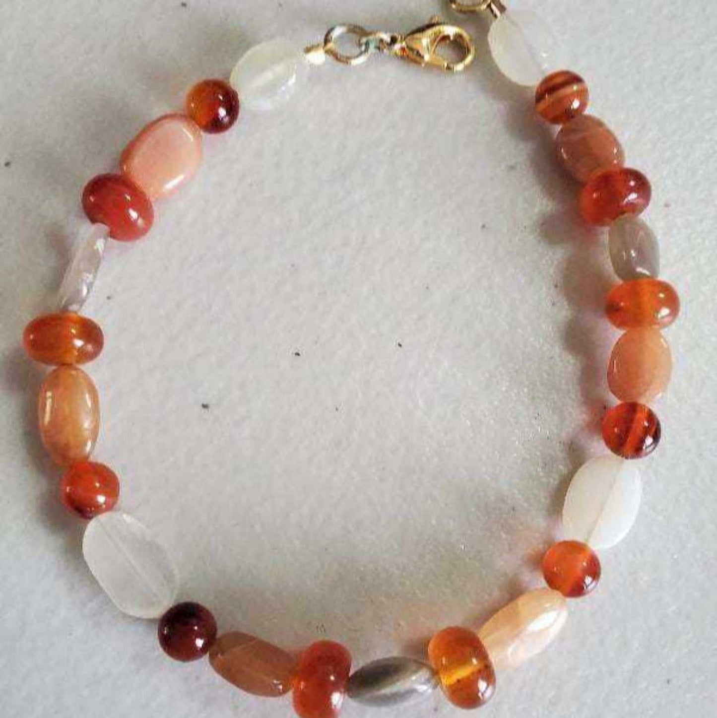 Carnelian and moonstone gemstone bracelet with brass accents and lobster claw clasp on white background