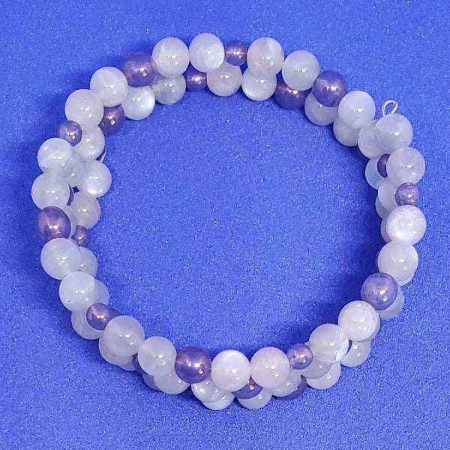 Rainbow Moonstone gemstone bracelet with purple and white beads on blue background