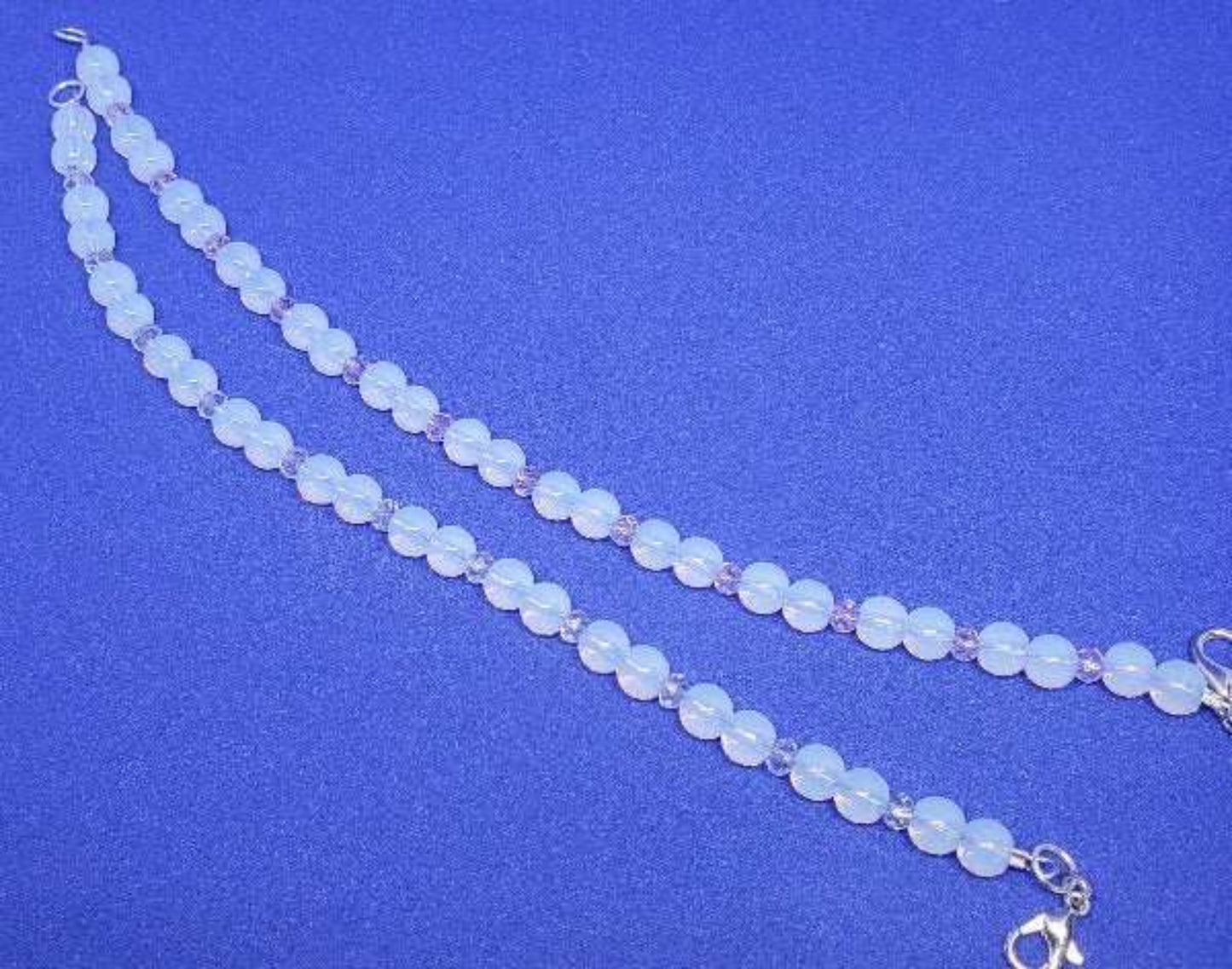 Opalite and crystal gemstone bracelet with lobster claw clasp on blue background