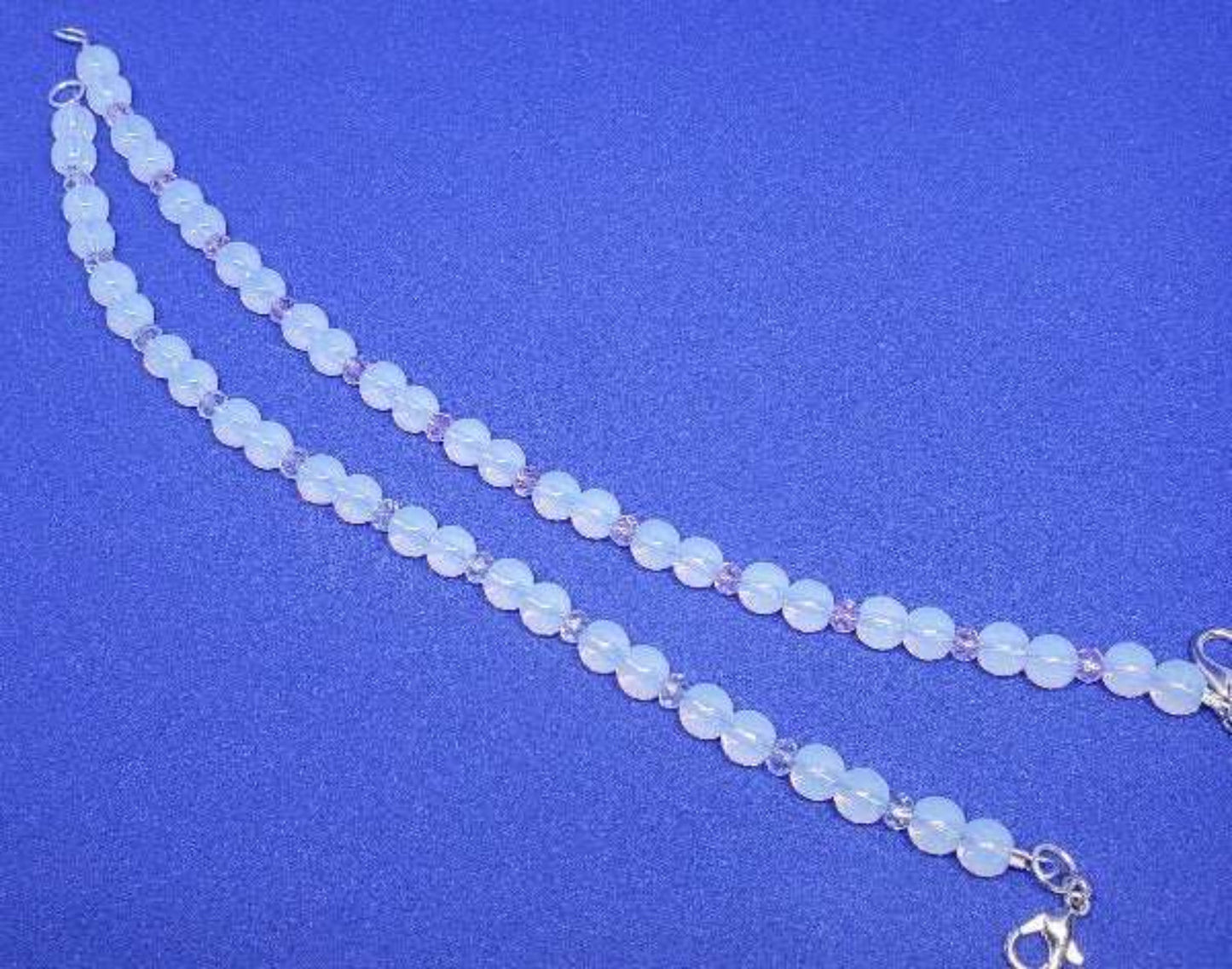 Opalite and crystal gemstone bracelet with lobster claw clasp on blue background