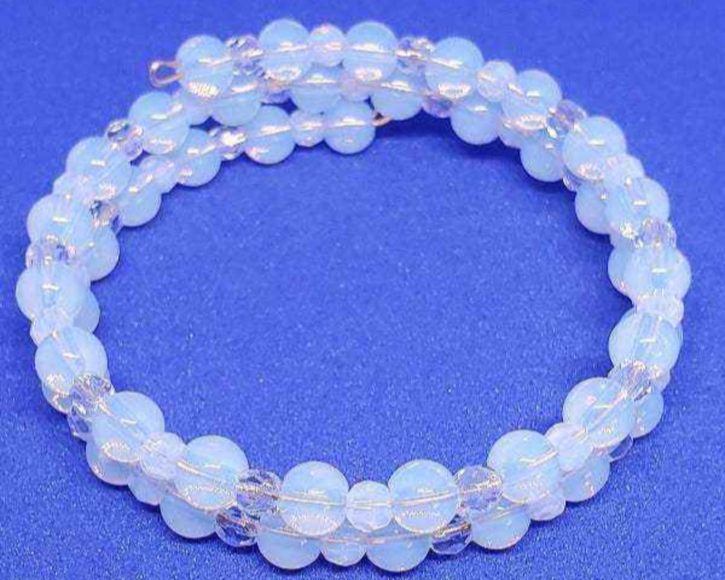 Opalite and crystal gemstone bracelet cuff with adjustable memory wire on blue background
