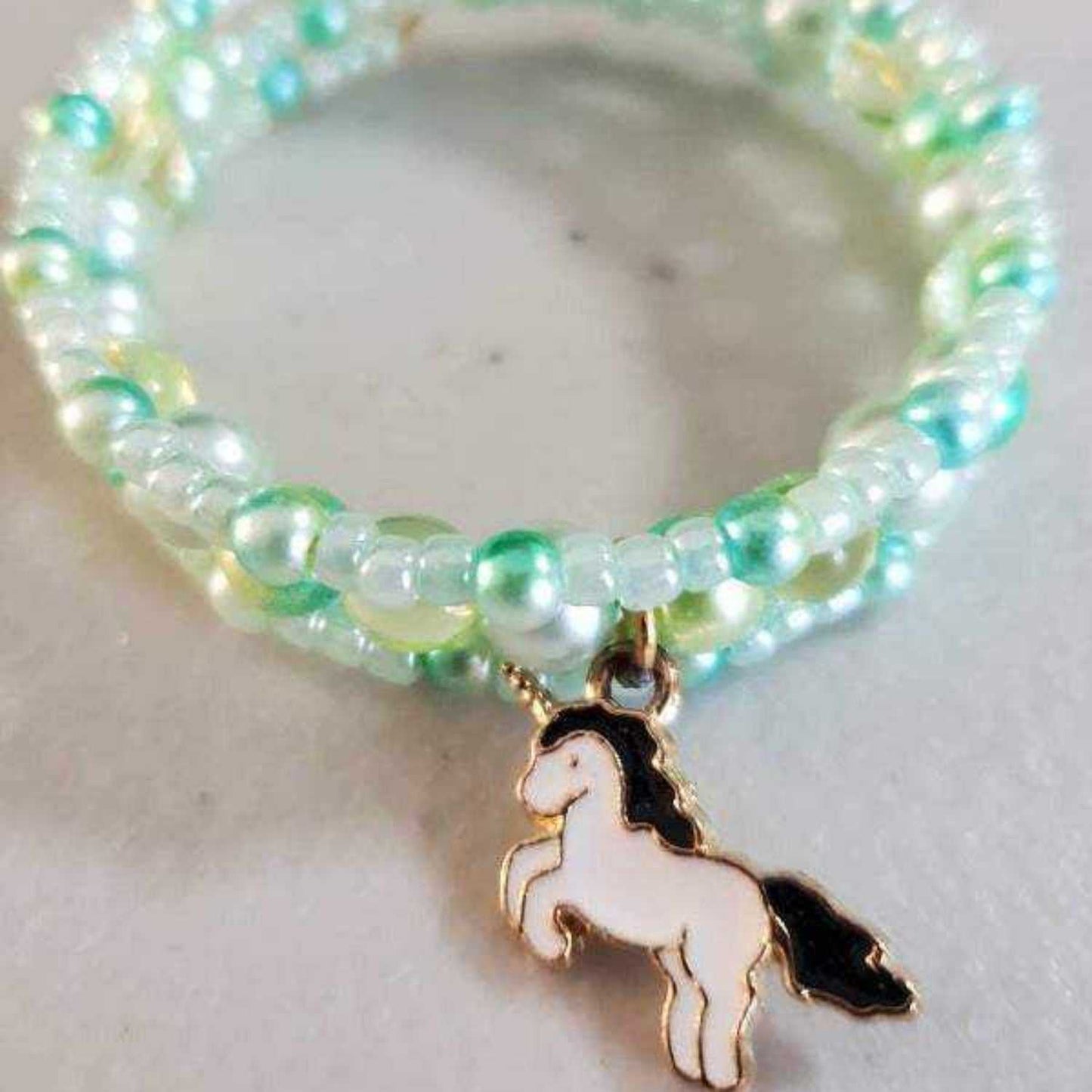 Colorful adjustable child cuff bracelet with a unicorn charm and glass beads