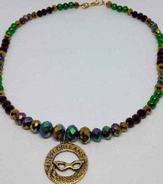 Charm necklace with Mardi Gras mask pendant and colorful glass and brass beads in purple, green, and gold.