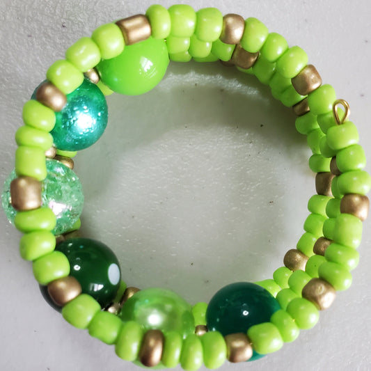 Green and gold beaded bracelet on a light gray background