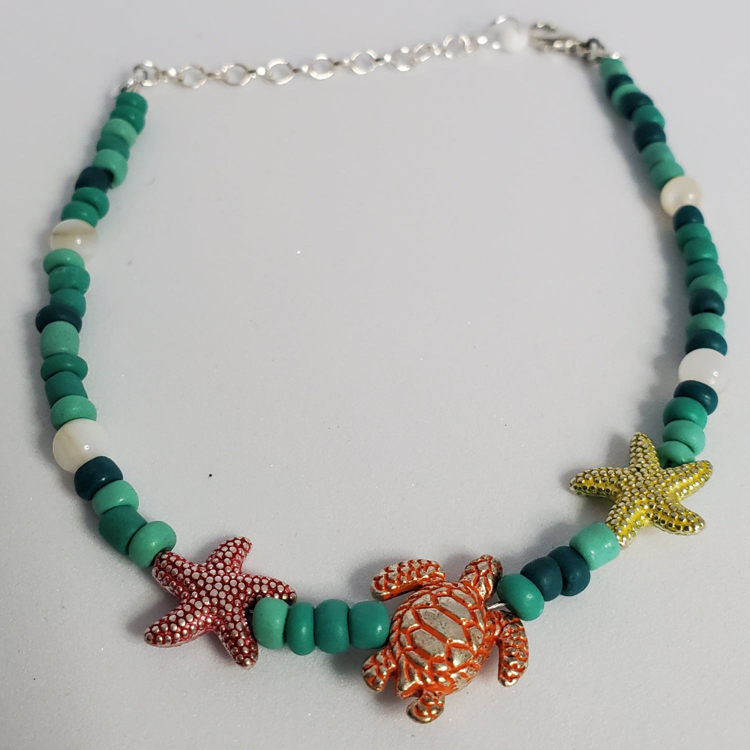 Anklet with starfish and turtle charms on a light gray background