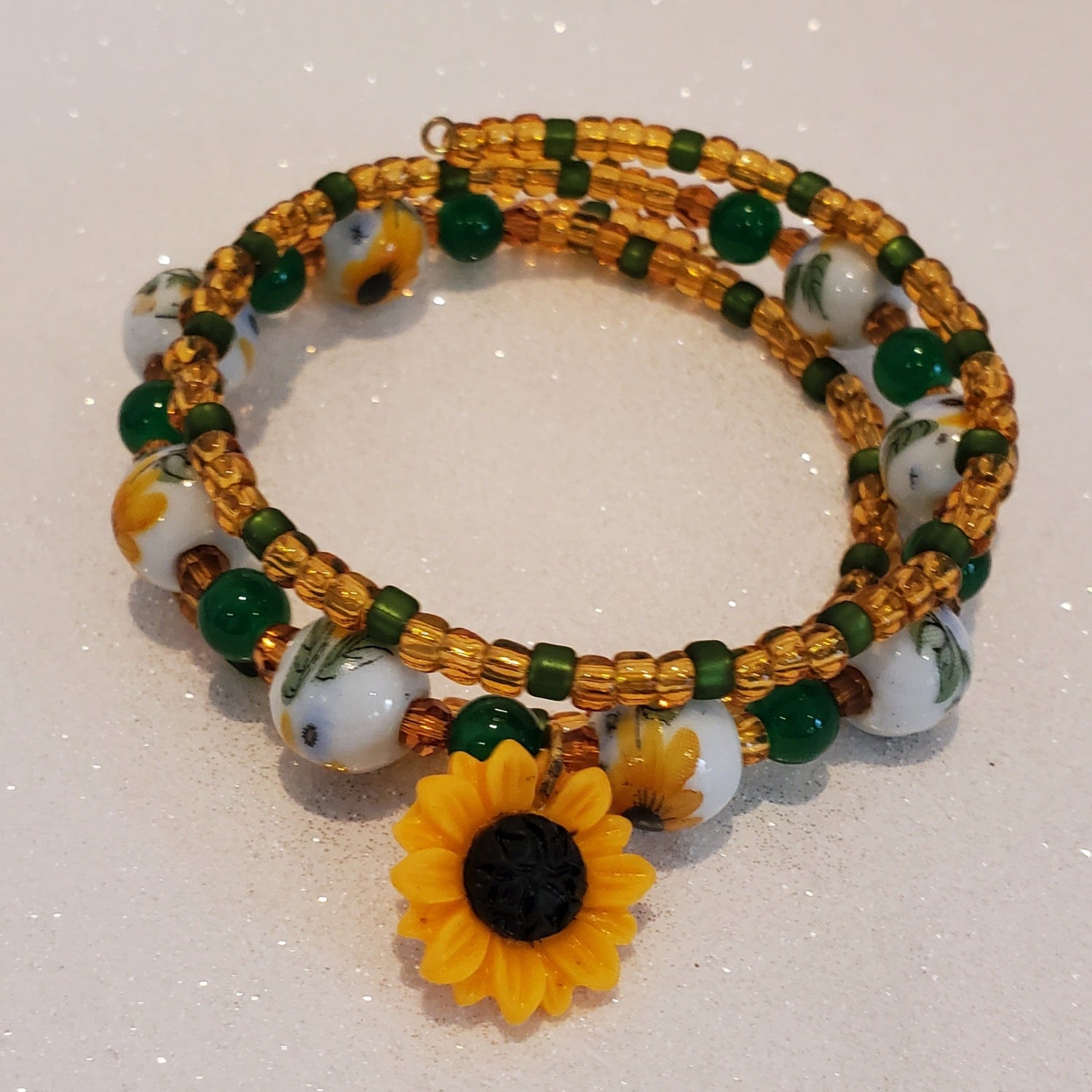 Beaded bracelet with sunflower charm on a white background