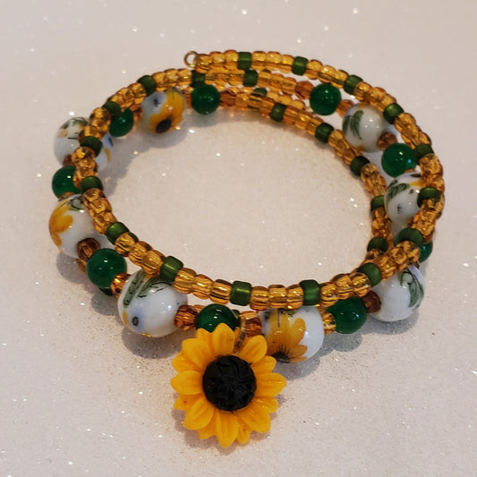 Beaded bracelet with sunflower charm on a white background