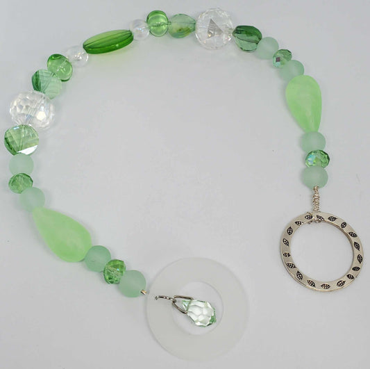 Green and clear mid-century modern style Crystal Suncatcher with vintage Lucite, acrylic beads, and glass elements in a circular design with a hanging ring.