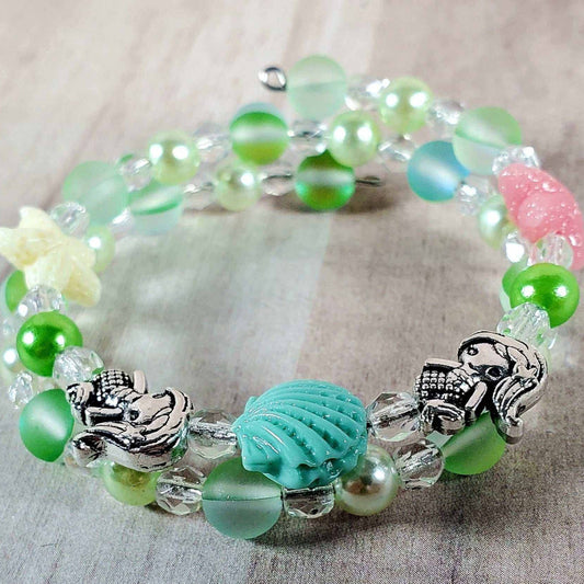 Child's mermaid bracelet with shimmering pearls, crystals, and sea-themed charms in pastel colors.