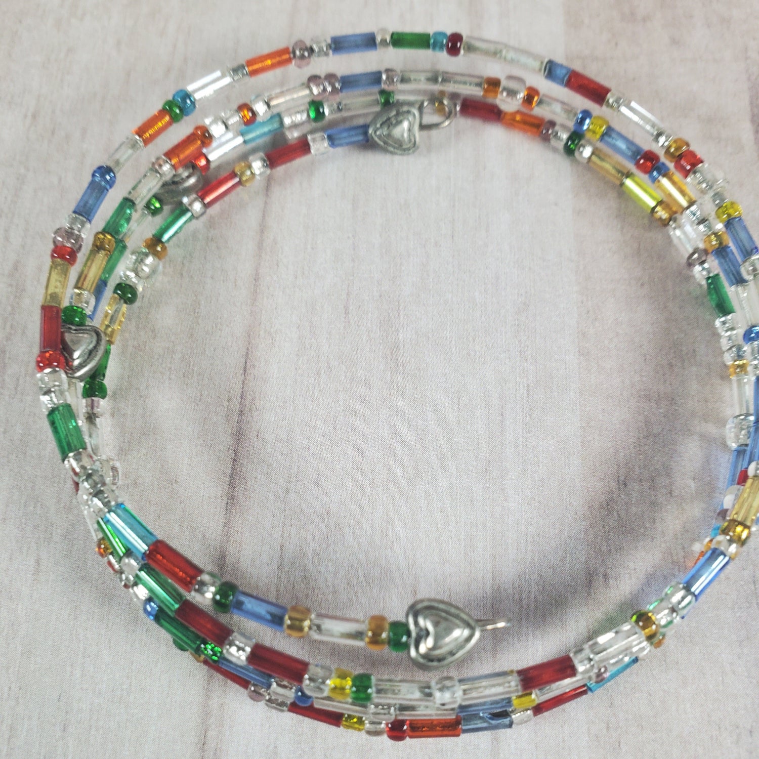 Colorful beaded necklace with heart-shaped clasps on a light fabric background