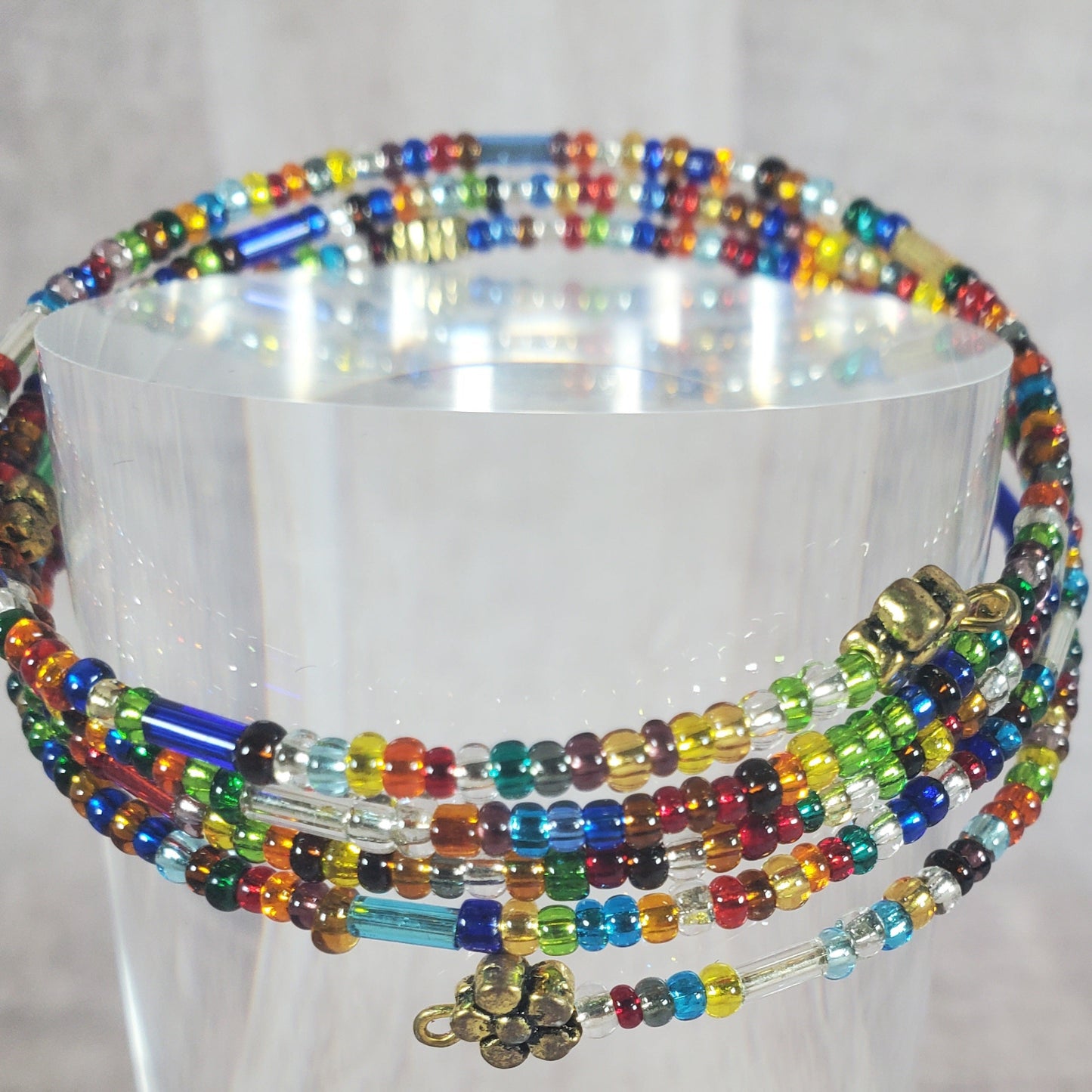 Colorful beaded necklace on a clear stand against a white background