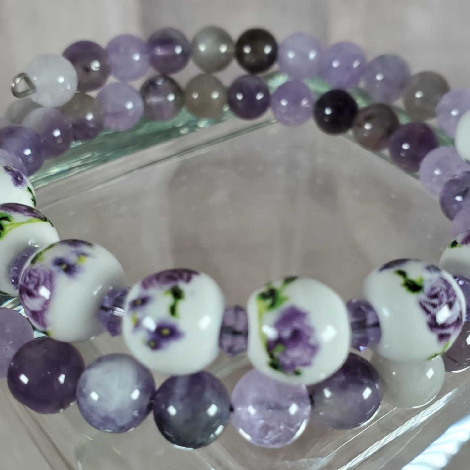 Floral bracelet with purple gemstone beads and white porcelain floral beads on memory wire.