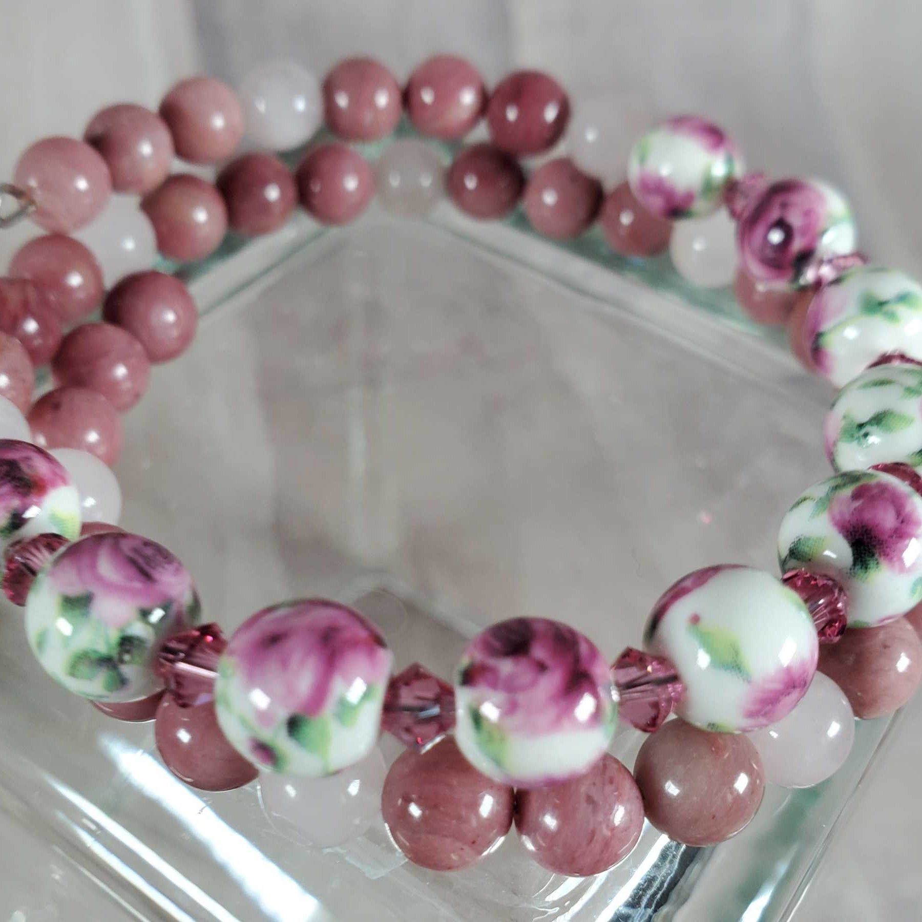 Floral bracelet with gemstone and porcelain floral beads in pink, white, and green tones on flexible memory wire.