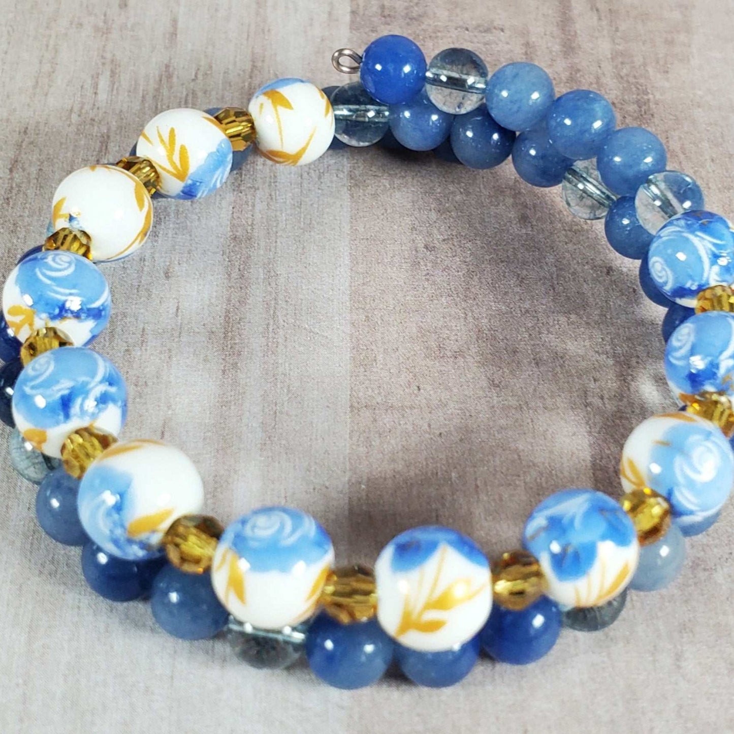 Floral bracelet with blue and white porcelain floral beads and blue gemstone beads on flexible memory wire