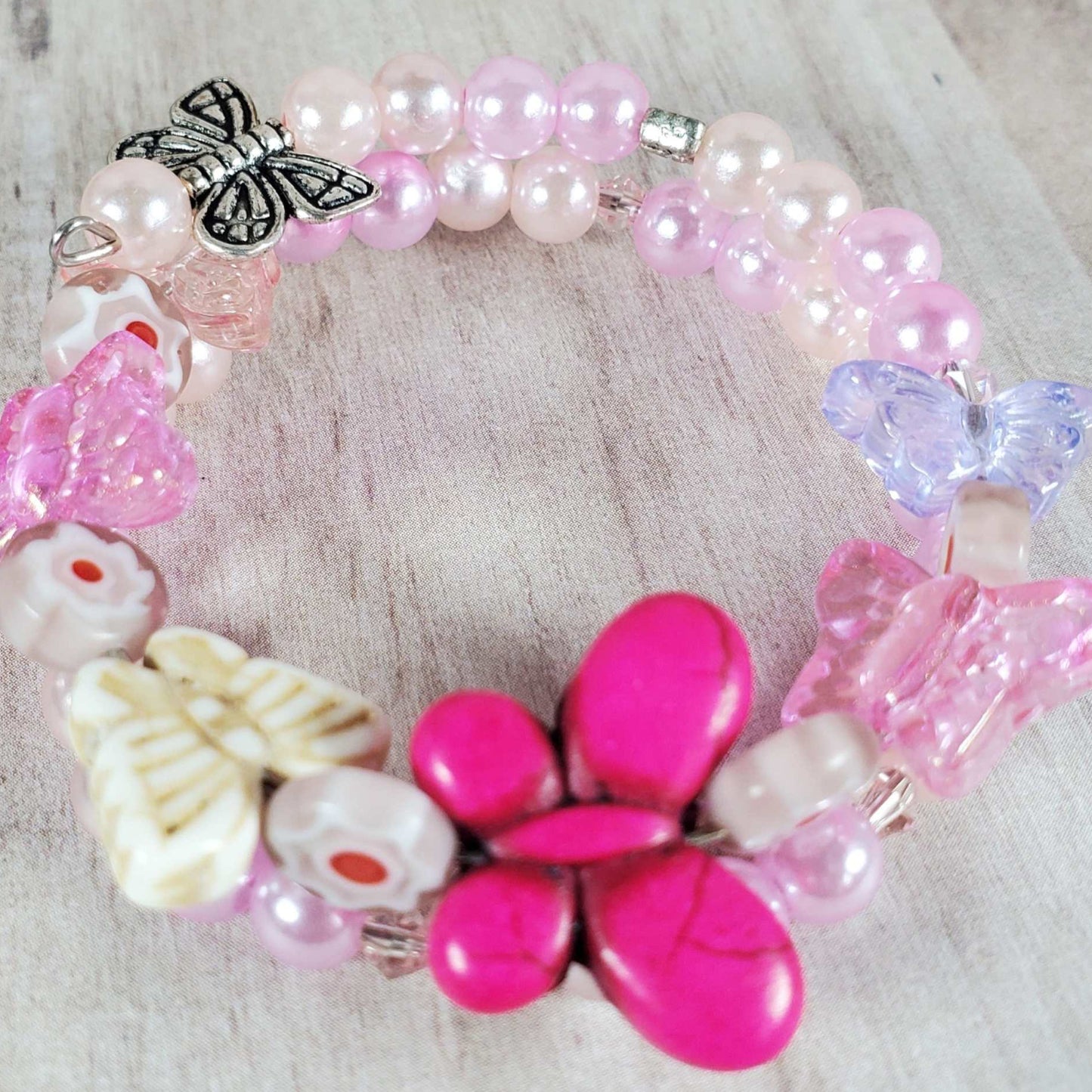 Colorful child's butterfly bracelet with pink, purple, and cream beads and butterfly charms on memory wire