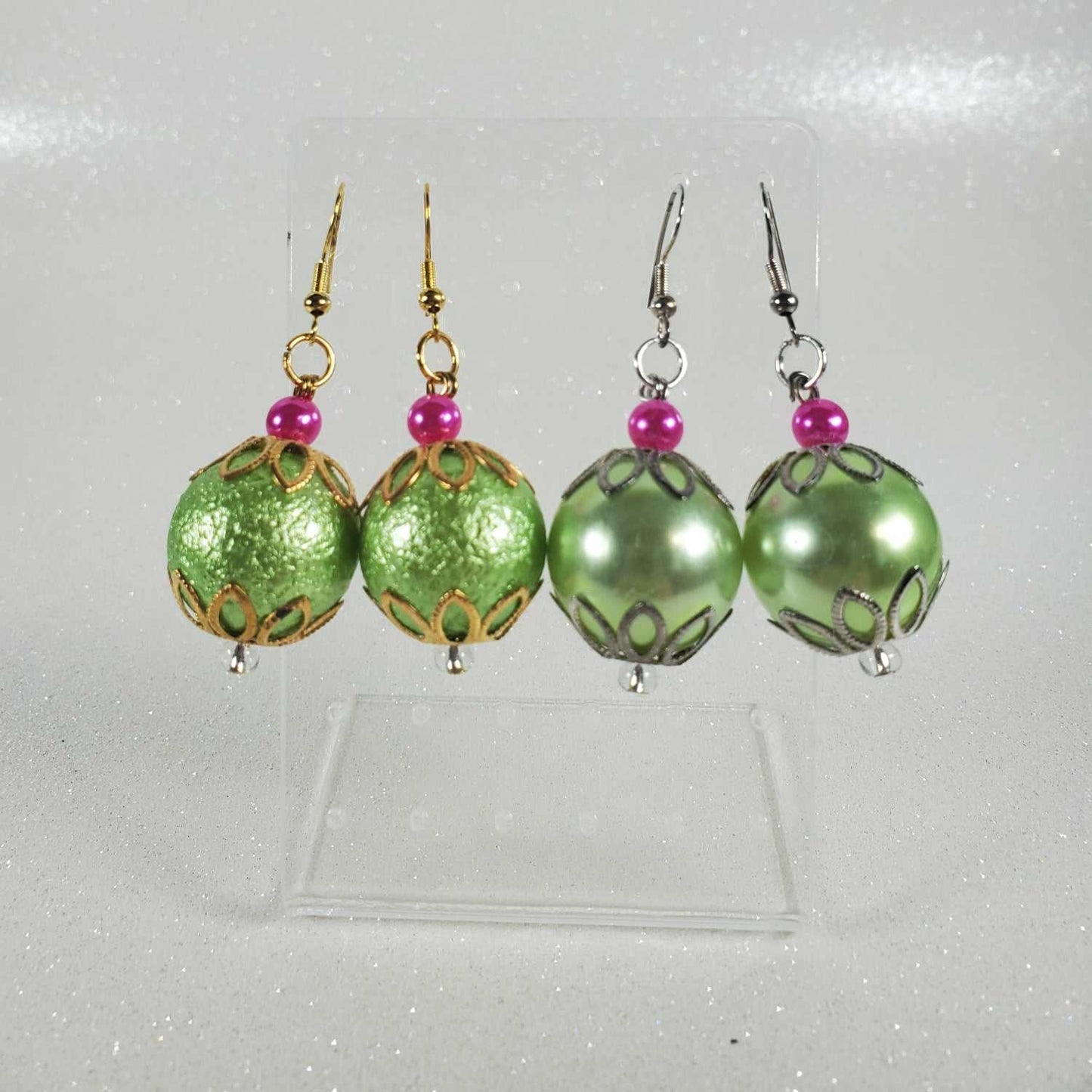 Green beaded earrings with pink beads on a white background