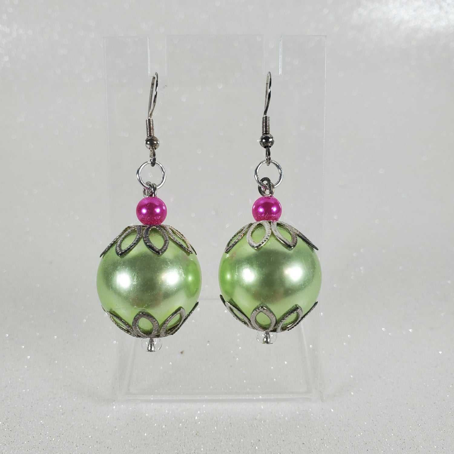 Pair of green and pink beaded earrings on a light gray background