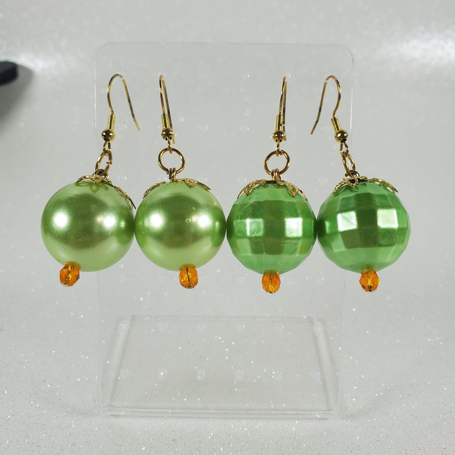 Green beaded earrings on a reflective surface
