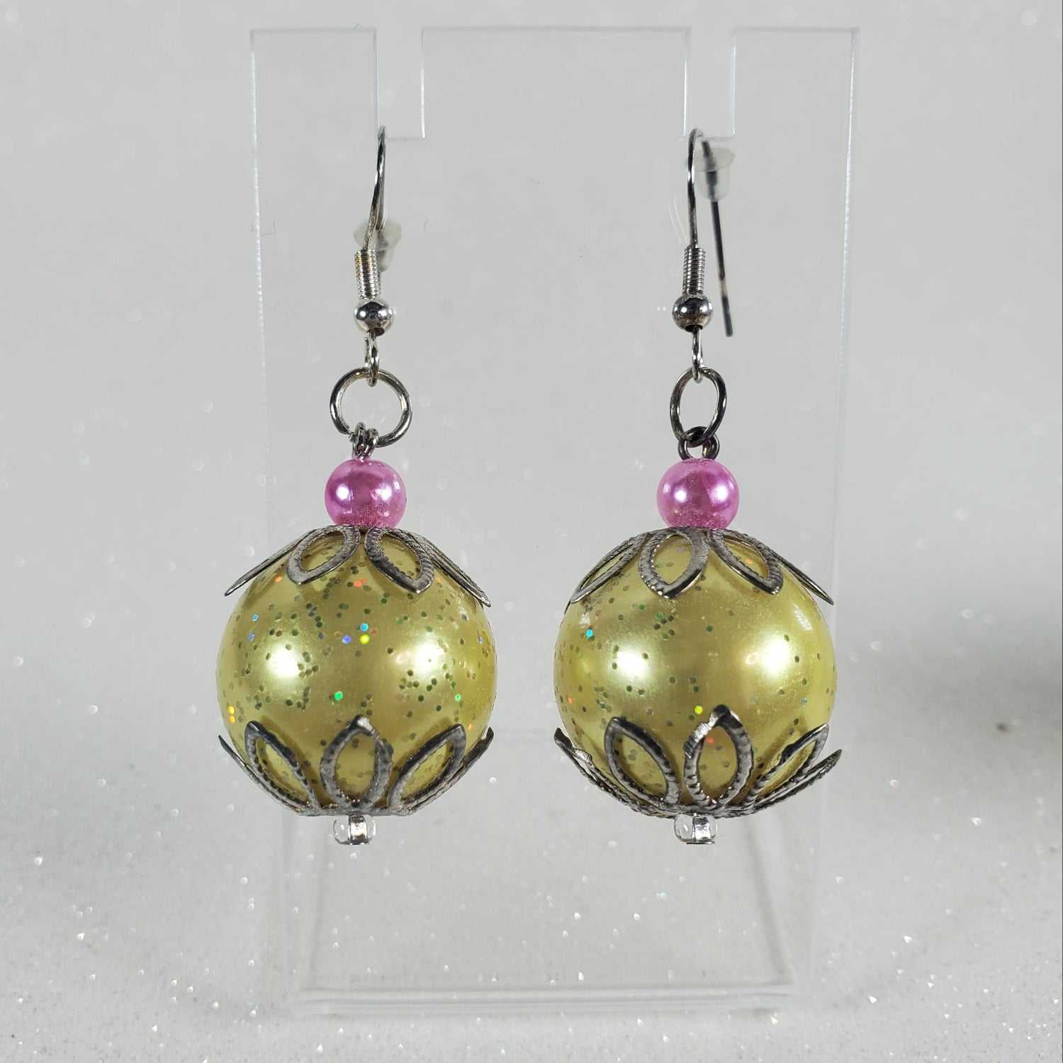 Pair of yellow beaded earrings with pink beads on a clear card against a light gray background