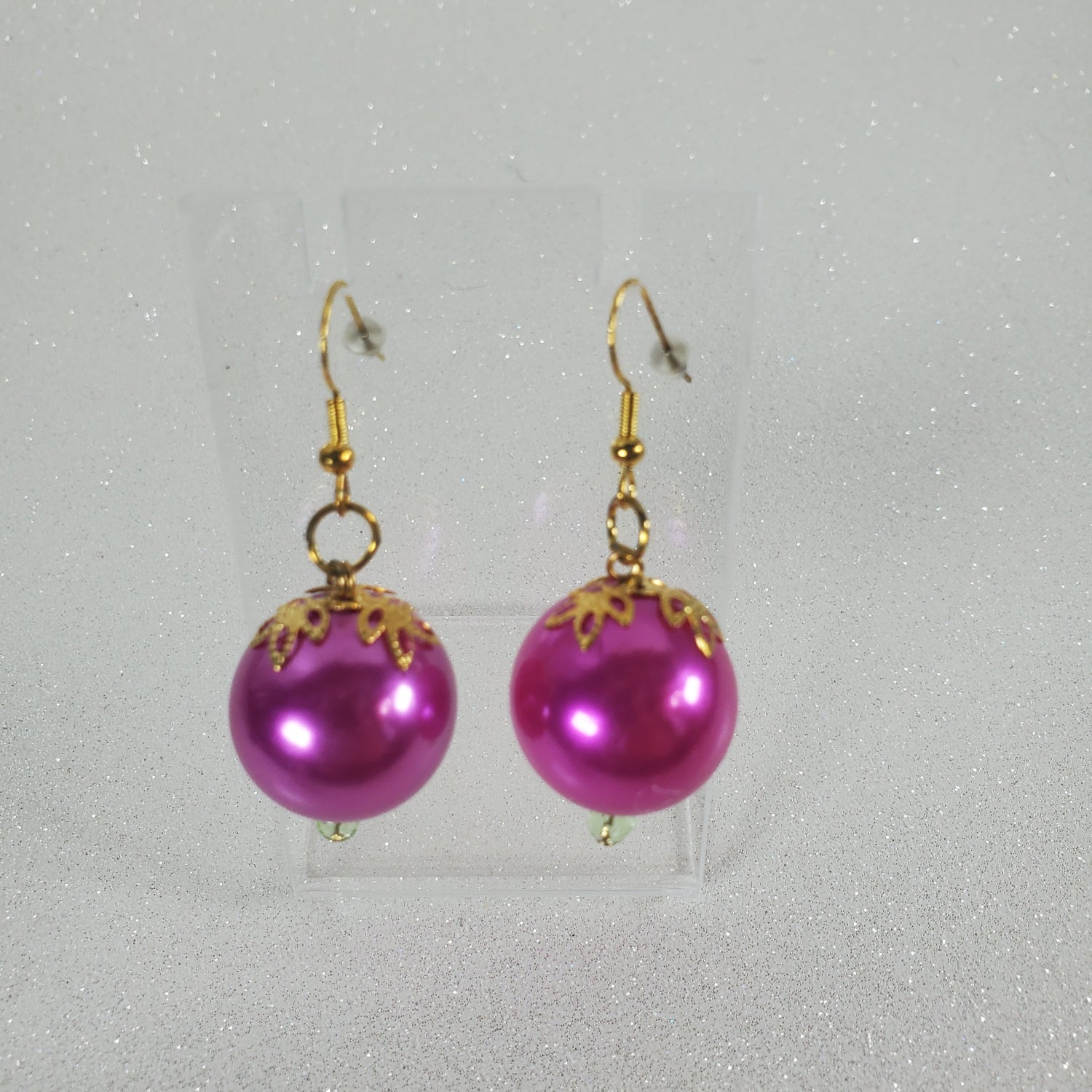 Fushia earrings with gold accents on a gray background