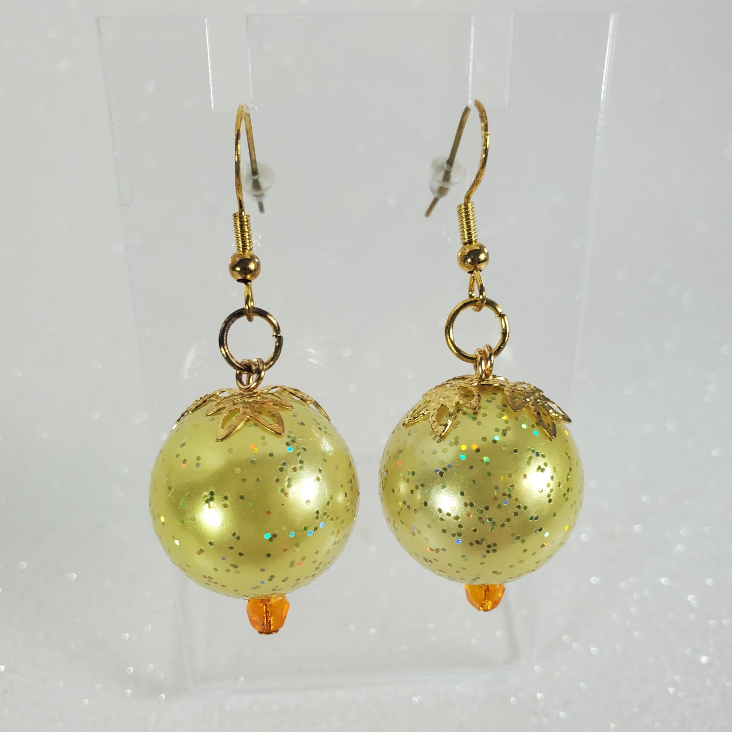 Gold glittery sphere earrings on a light gray background