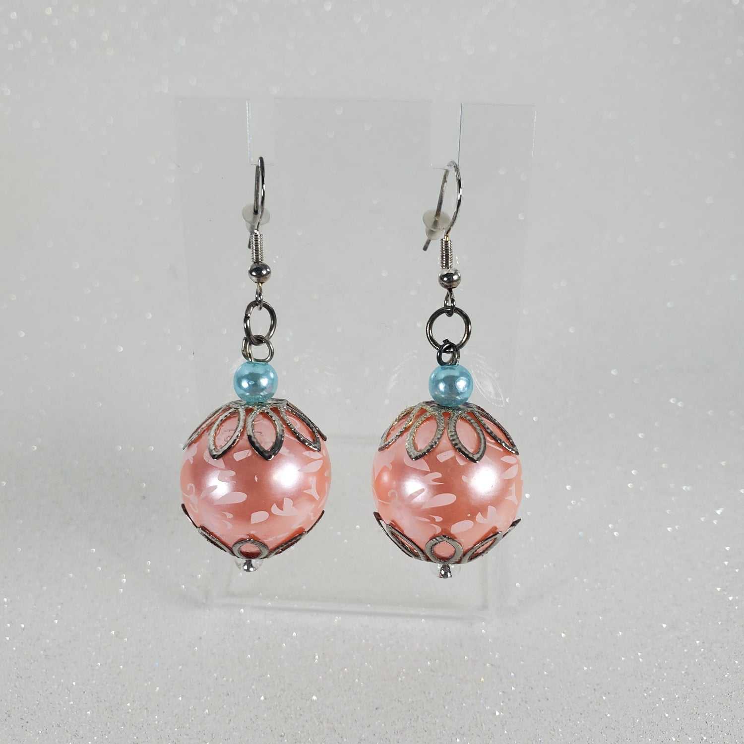 Pair of peach beaded earrings on a clear plastic card against a light gray background