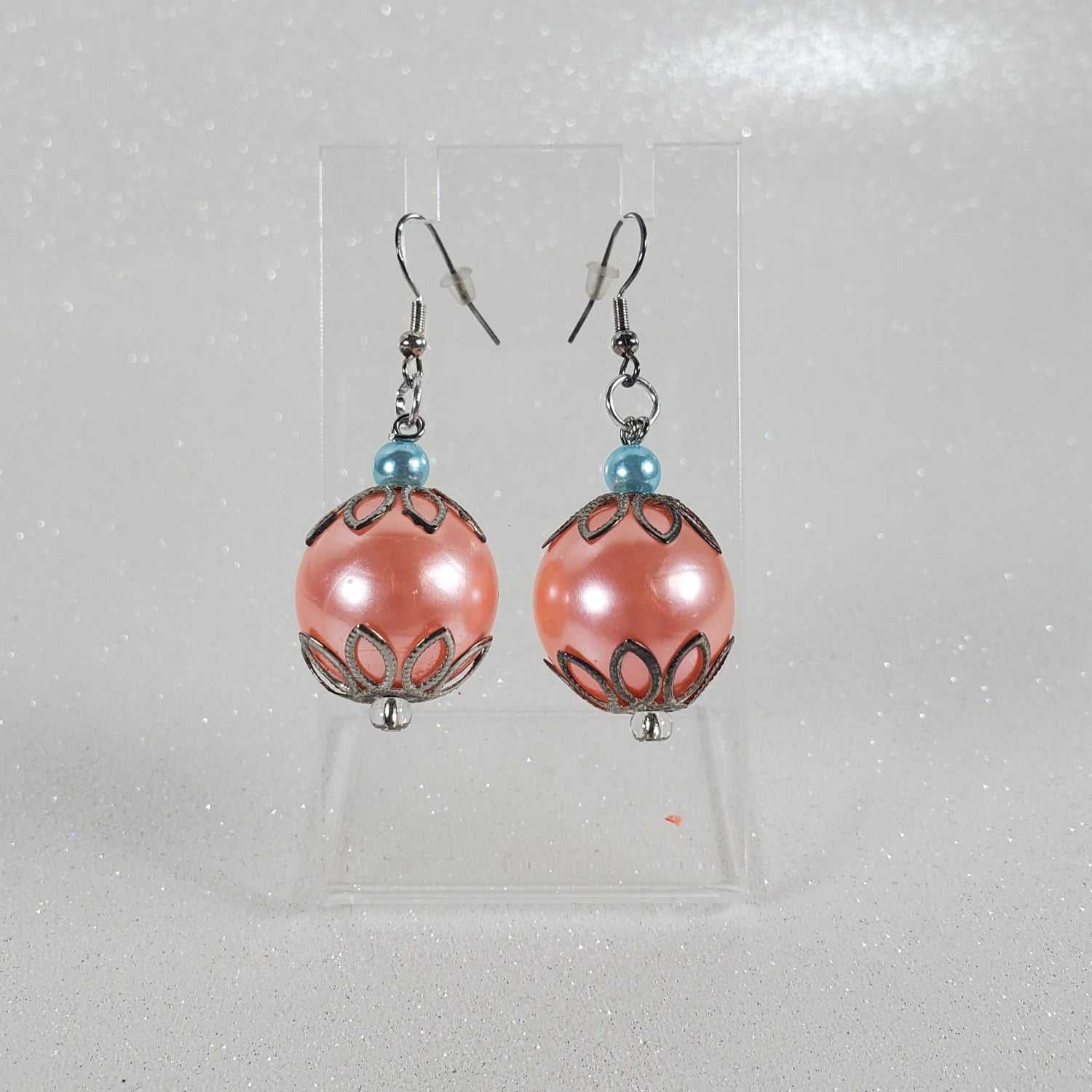 Pair of peach beaded earrings on a clear card against a light gray background